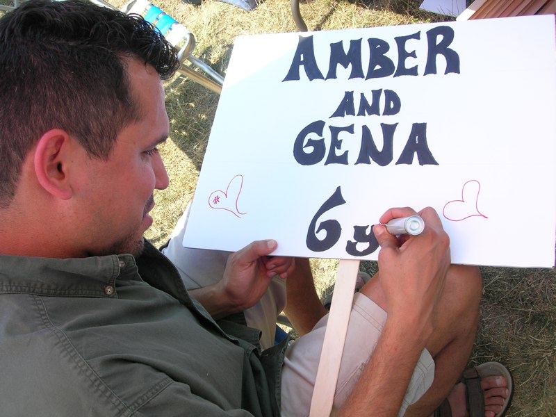Baltazar creating a sign for Amber & Gena with a marker on poster board.